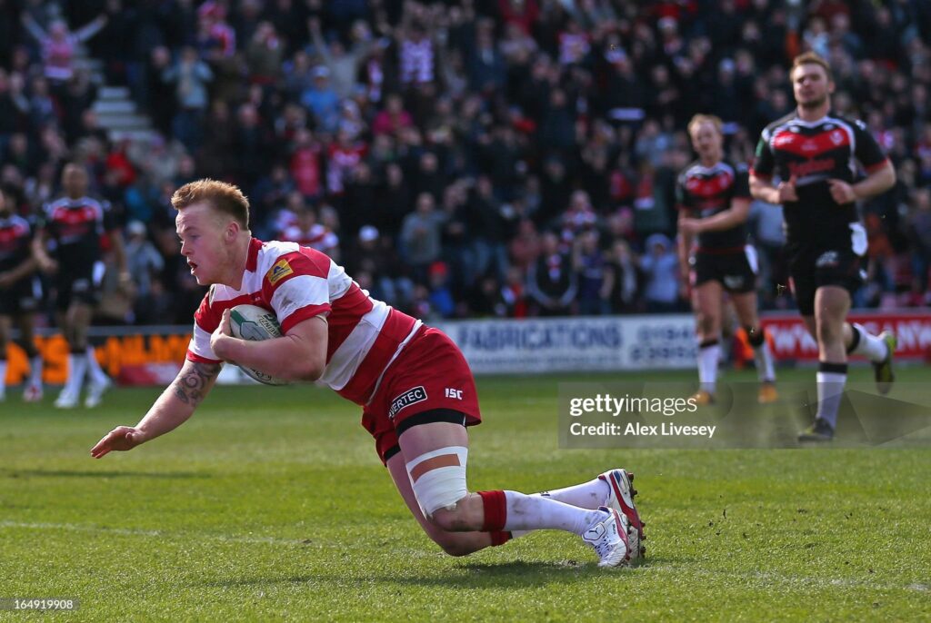 WIGAN, ENGLAND - MARCH 29:  Dom Crosby of Wigan Warriors dives over the line to score his try during the Super League match between Wigan Warriors and St Helens at DW Stadium on March 29, 2013 in Wigan, England.  (Photo by Alex Livesey/Getty Images)